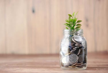 Planta que crece de un frasco lleno de monedas de plata, simbolizando el crecimiento financiero