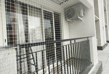 Technician carefully fitting a safety net on a high-rise balcony in Mumbai.