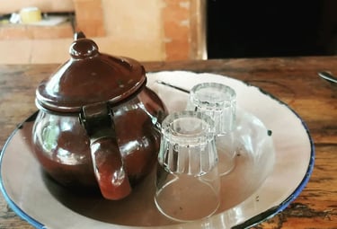 Une théière et deux verres posés sur une table en bois, créant une ambiance chaleureuse et conviviale.