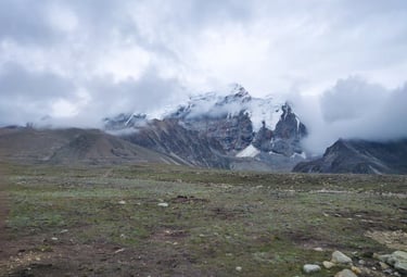 North East trip details - A soulful view of snow-capped Himalayan peaks partially hidden by thick white clouds.