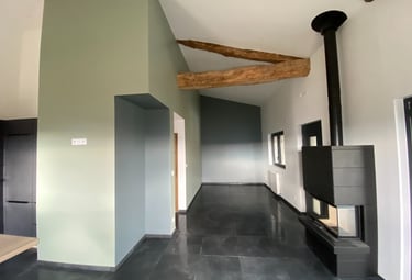 Pièce rénovée avec poutres apparentes et cheminée moderne.