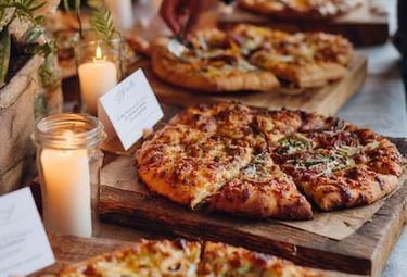 Exhibición de catering de pizza gourmet rústica, con velas y arreglos florales.