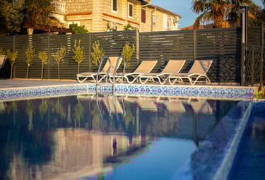 Luxurious infinity pool with sea and mountain views at sunset, lounge chairs and stone features at V