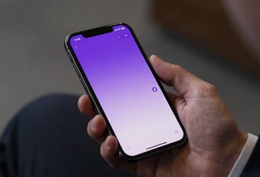 A close-up shot of a smartphone displaying a sleek, minimalist chat interface with royal amethyst and soft lavender highlights, held by a person in a professional suit.