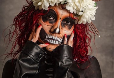 Mujer con maquillaje de calavera de azúcar del Día de Muertos con corona floral blanca y cabello roj