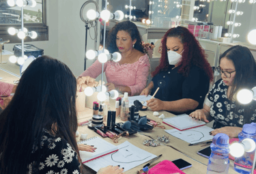 Estudiantes practicando el mapeo de gráficos faciales en una clase de maquillaje profesional