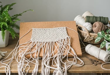 Proyecto de tapiz de macramé hecho a mano fijado con alfileres a un tablero de corcho.
