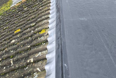 Professional EPDM rubber flat roof installation with lead flashing connected to a tiled pitched roof.