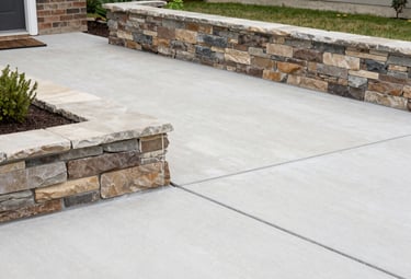 A freshly poured concrete patio bordered by a sturdy retaining wall in a Houston backyard.