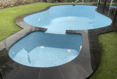  Freeform fully tiled luxury pool with pale blue water, light mosaic tiling and dark curved coping