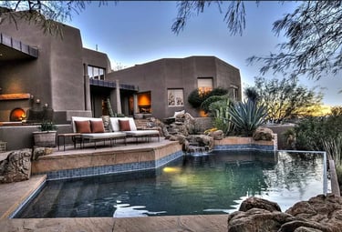 desert inspired Lagoon-style pool with, natural stone edging, and dark green–teal interior