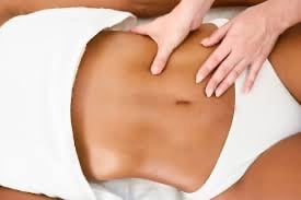 Professional therapist performing a relaxing abdominal stomach massage for lymphatic drainage.