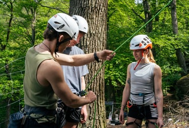 Outdoor climbing course on the rock, instructor Christoph Steiner explains belay techniques.