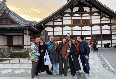 A group of friends posing in front of a traditional Japanese Buddhist temple in Kyoto during sunset.