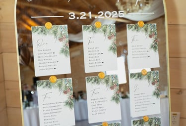 Elegant gold arched mirror wedding seating chart with pine needle cards and wax seals.