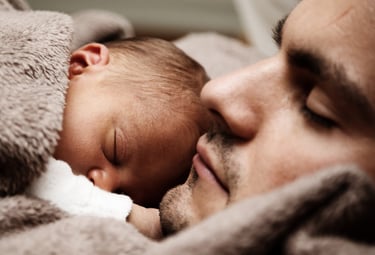 Hombre dormido con su bebé dormido encima de él