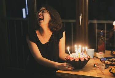 une femme rit aux éclats devant son gateau d'anniversaire, par zohra Elmes 