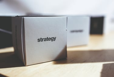 caixa-branca-em-cima-de-uma-mesa-na-caixa-está-ecrita-a-palavra-strategy