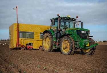 A tractor in a field with a planter behind