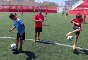 Niños aprendiendo trucos de freestyle fútbol como la vuelta al mundo en una masterclass en Barcelona