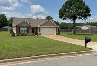 Well-kept Savannah, TN home with a large trimmed backyard tree, showing professional removal of low-