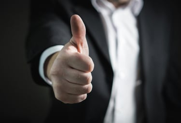 A businessman in a suit giving a thumbs up gesture for success and positive approval.