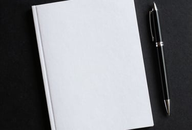 A sleek black notebook with gold embossed logo resting beside a fountain pen.