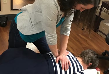 Chiropractor adjusting patient’s mid back showing a spinal manipulation.