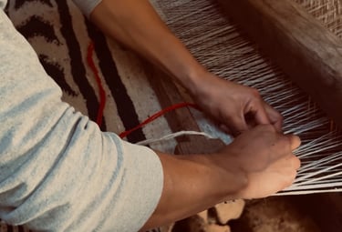 Un artesano tejiendo a mano un tejido de lana estampado en un telar de madera tradicional.