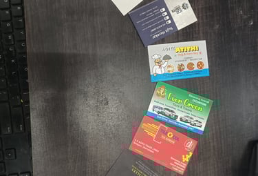 Collection of business cards for local Indian services like tours, hotels, and tile adhesives on a dark desk.
