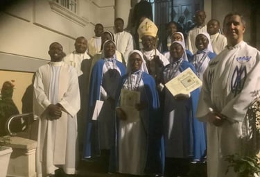 A group of Catholic clergy, including a bishop, priests, and nuns in blue habits, posing for a photo.