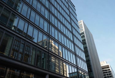 Photography of a sleek, contemporary commercial glass building in the City of London, reflecting a bright blue sky, conveying professional growth and urban success.