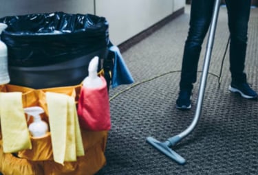 Vacuuming carpet near trashcan