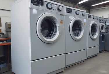 A storefront features various household appliances and furniture. Several refrigerators are placed outside, alongside couches and chairs. The background shows a building with signage and open doorways. A person stands near the entrance.