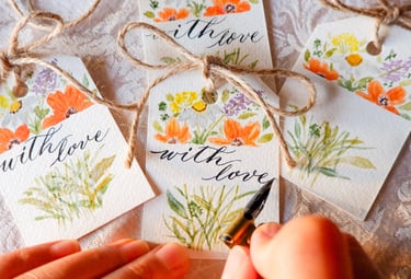 NYC calligrapher writing the words “with love” for a gift tag with handmade watercolor florals
