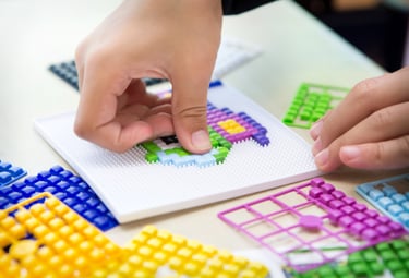 A child creates a picture using colored silicone pixel squares on the baseplate