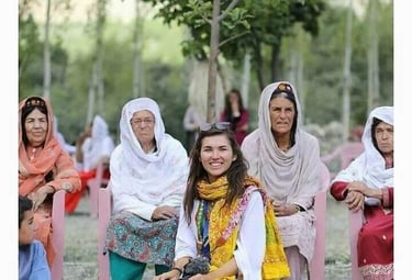 Eva zu Beck stands with local Hunza women, all in vibrant traditional attire and signature caps, sha