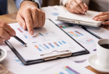 Dos personas revisando documentos y gráficos en una mesa, representando asesoría profesional con seg