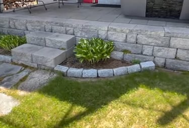 grey brick patio on the rear of a house with steps made of stone with manicured lawn