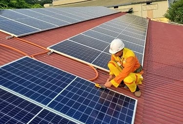 Professional technician installing solar panels on a red industrial rooftop for renewable energy.