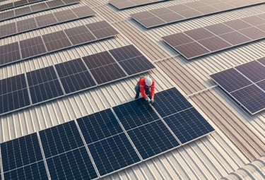 A technician installing solar panels on a commercial metal rooftop for renewable energy.