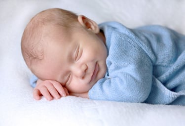un bébé heureux dort sur une couverture dans un lit