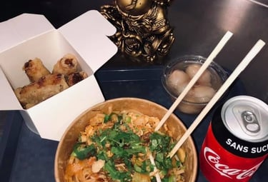 a bowl of noodles with chopsticks and a soda can be seen
