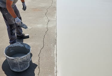 a man is putting a resurfacing treatment on  a concrete slab in a driveway