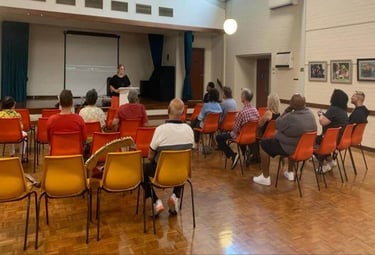 a person standing in front of a room filled with people listening