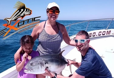 a woman , a man and a girl holding a fish caught on a boat at San Jose del cabo marina.