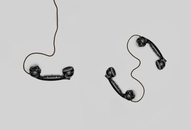 A beige solid background with three wired old fashioned phones places at different angles