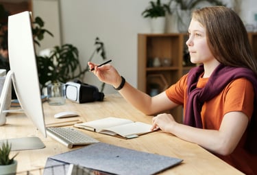 a student sitting at a table with a computer during online tuition