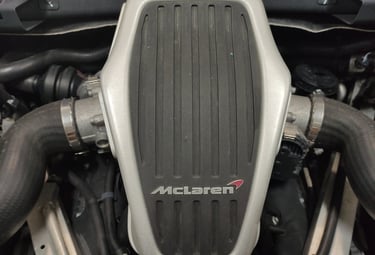 an Enlab close up of a McLaren sports car engine with a motorbike