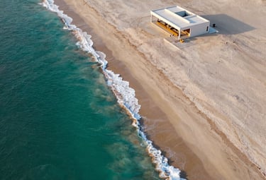 Aerial view of a pristine luxury beach property on the northern coast of Peru. Turquoise water, ivory sand, minimalist architectural structure, high contrast sunset lighting.